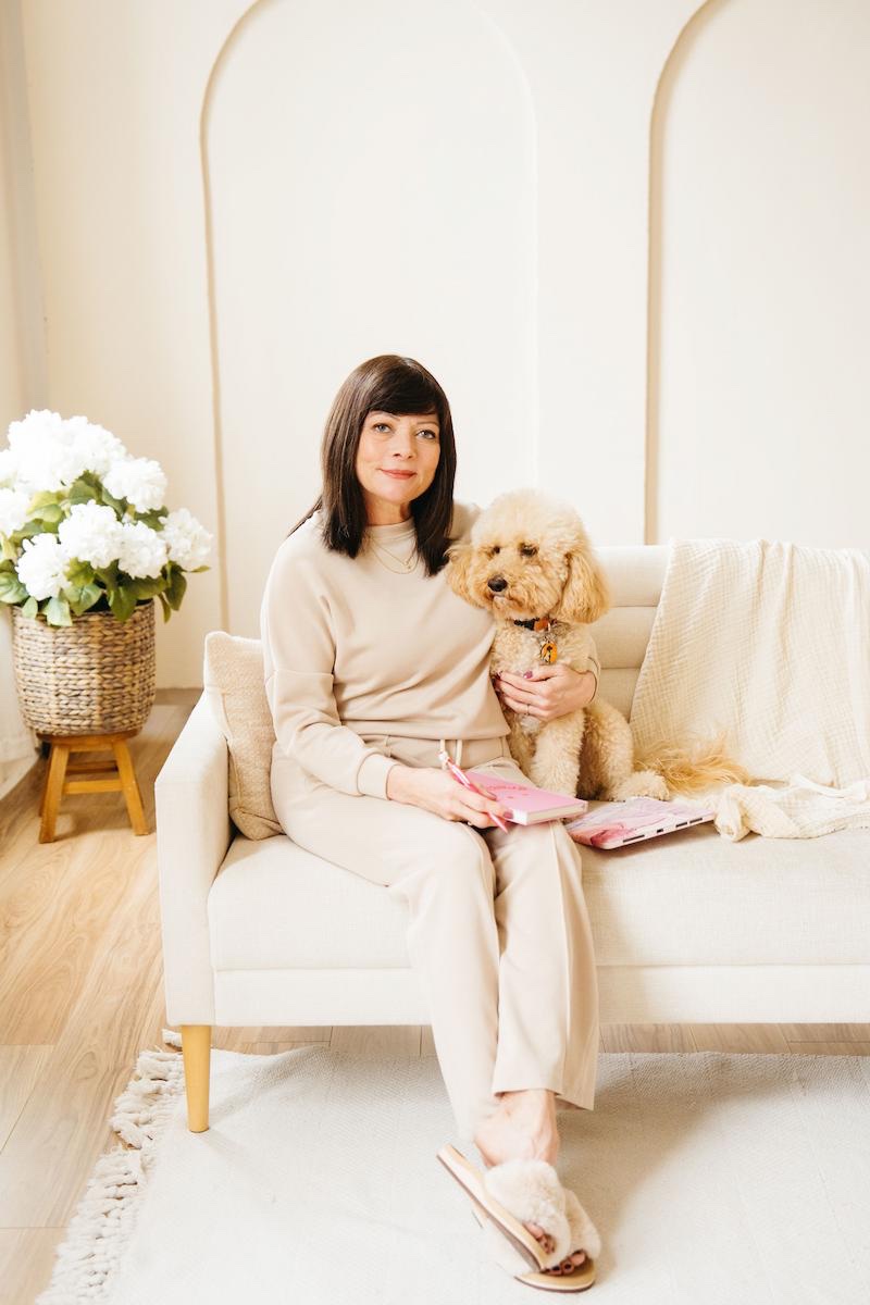 Terii and her dog Peaches on a cream couch with white flowers, soft morning light